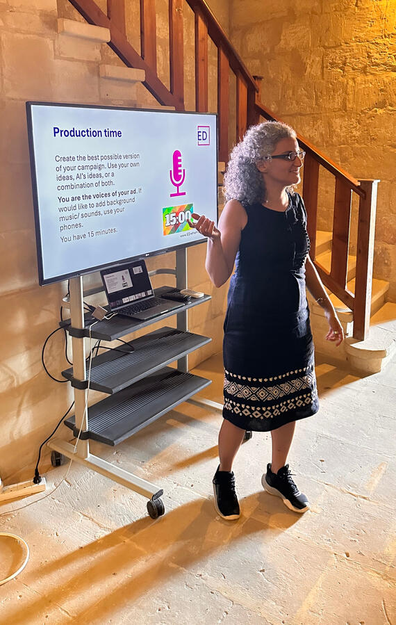Sondes Gharbi facilitates an EDreframe workshop on project-based learning and AI during Erasmus Days in Gozo. Sondes Gharbi speaks beside a presentation screen during an EDreframe workshop in Gozo.